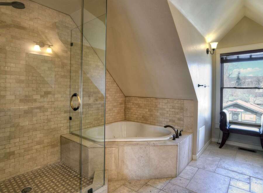 Step into luxury with this stunning bathroom featuring a corner jacuzzi tub and a separate glass-enclosed shower.