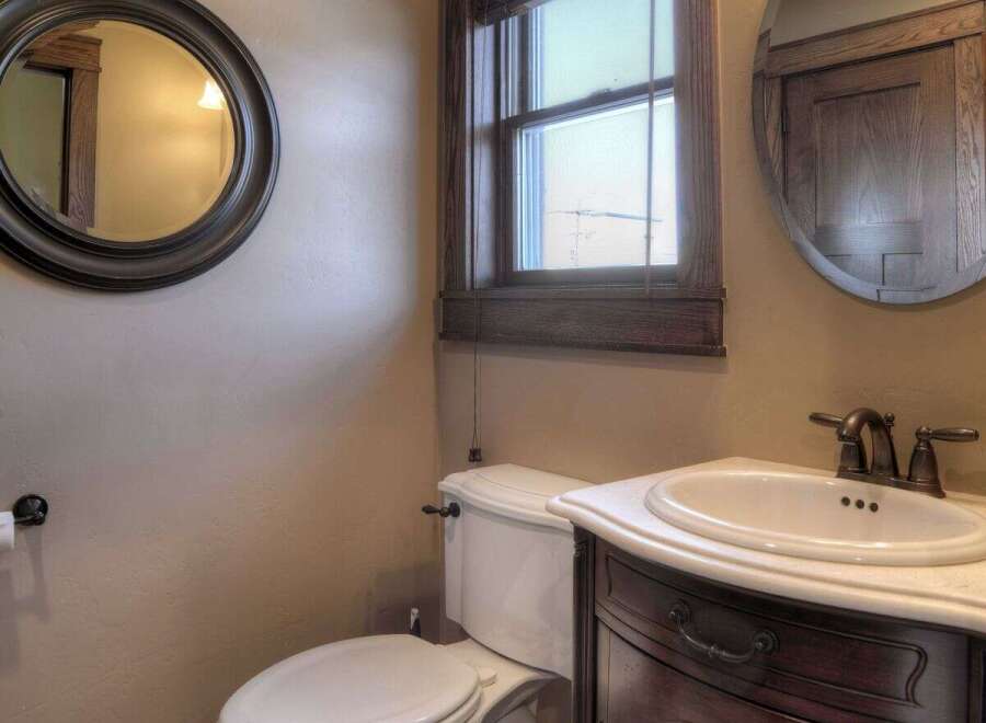 Step into this beautifully designed bathroom, featuring a classic vanity with a marble countertop and a stylish round mirror.