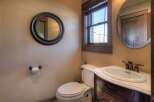 This charming bathroom features a classic design with a round mirror, a wooden vanity, and a toilet.