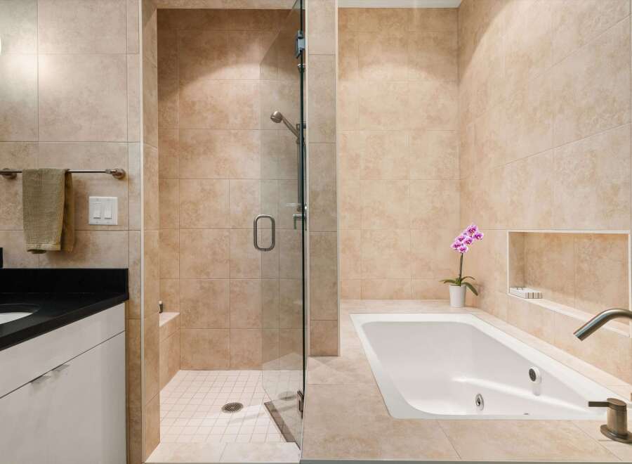 Step into luxury with this stunning bathroom featuring a sleek shower and a relaxing bathtub.