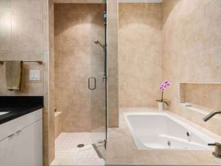 Step into luxury with this stunning bathroom featuring a sleek shower and a relaxing bathtub.