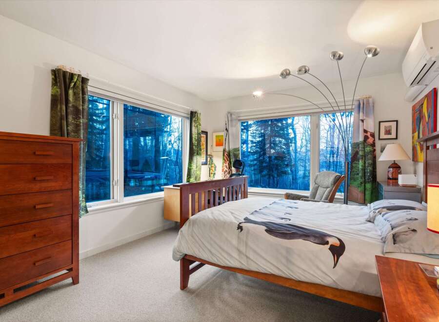 This stunning bedroom boasts a serene ambiance with its large windows offering picturesque views.