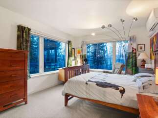 This stunning bedroom boasts a serene ambiance with its large windows offering picturesque views.