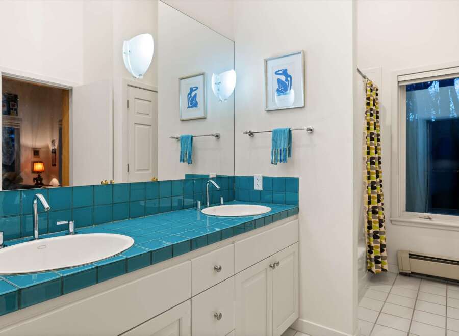 This stunning bathroom features a vibrant teal tiled countertop, creating a bold and stylish focal point.