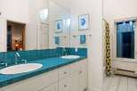 This stunning bathroom features a vibrant teal tiled countertop, creating a bold and stylish focal point.