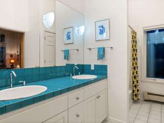 This stunning bathroom features a vibrant teal tiled countertop, creating a bold and stylish focal point.