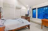 This cozy bedroom offers a serene retreat with its vaulted ceilings and ample natural light.