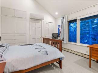 This cozy bedroom offers a serene retreat with its vaulted ceilings and ample natural light.