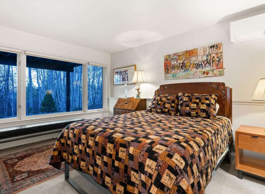 This cozy bedroom features a comfortable bed with a unique quilt and decorative pillows, creating a warm and inviting atmosphere.