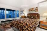 This cozy bedroom features a comfortable bed with a unique quilt and decorative pillows, creating a warm and inviting atmosphere.