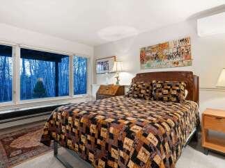 This cozy bedroom features a comfortable bed with a unique quilt and decorative pillows, creating a warm and inviting atmosphere.