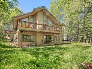 Nestled amidst lush greenery and tall trees, this charming home offers a serene retreat.