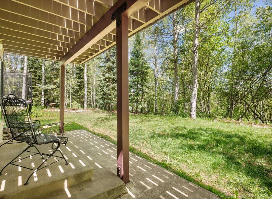 Enjoy the serene mountain setting from this covered patio, perfect for relaxing amidst the tall trees.