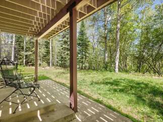 Enjoy the serene mountain setting from this covered patio, perfect for relaxing amidst the tall trees.