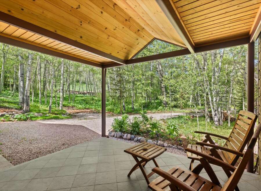 Enjoy the serene mountain setting from this charming covered porch, perfect for relaxing amidst the aspen trees.