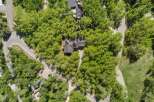 Discover this stunning aerial view of a modern home nestled amidst lush greenery and mature trees.