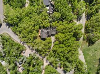 Discover this stunning aerial view of a modern home nestled amidst lush greenery and mature trees.