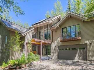 Discover this stunning modern home featuring a striking architectural design with expansive windows and a unique balcony overlooking the property.