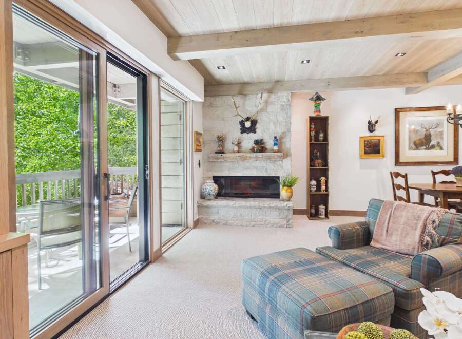 Experience rustic elegance in this mountain-inspired living room, featuring a striking stone fireplace and exposed wood beams.