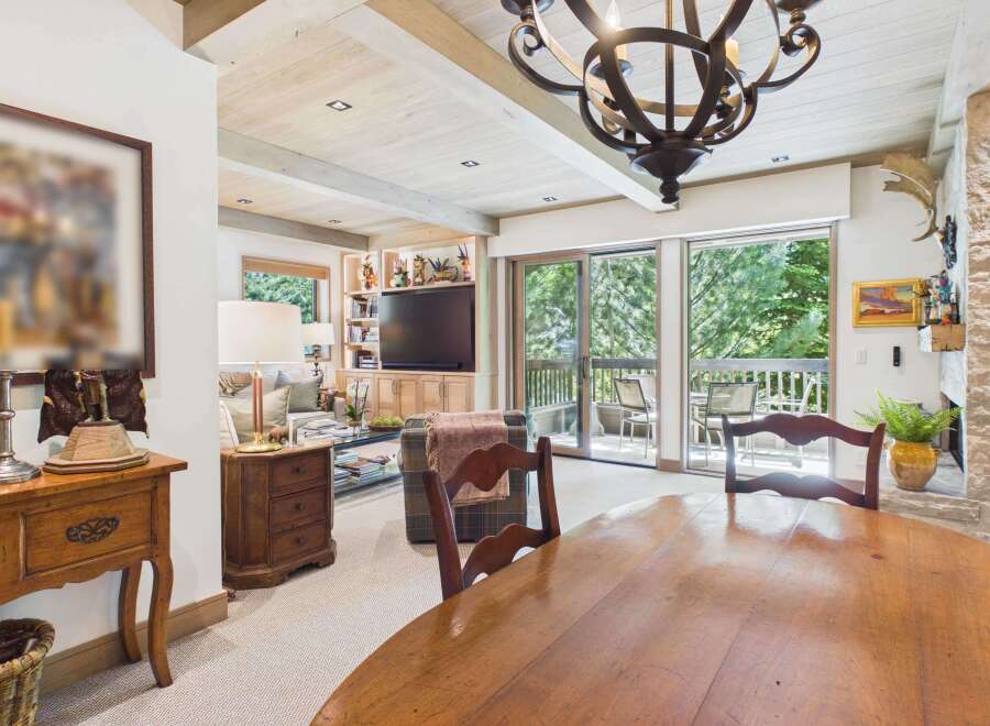 Experience rustic charm in this inviting living and dining area, featuring exposed wooden beams and a stone fireplace.