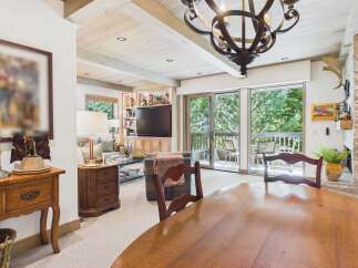 Experience rustic charm in this inviting living and dining area, featuring exposed wooden beams and a stone fireplace.