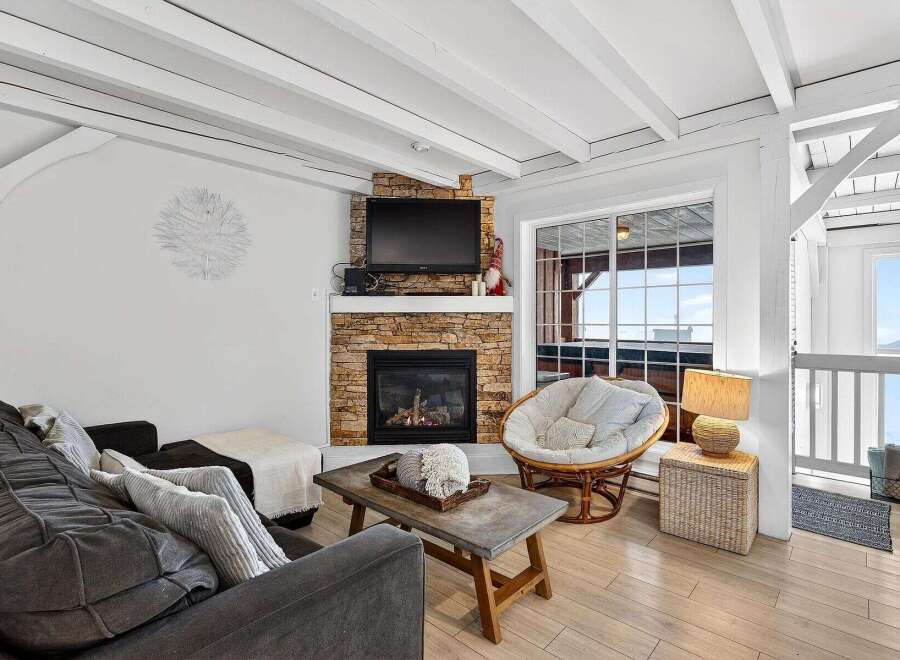 Discover the charm of this cozy living space, featuring a stunning stone fireplace and a comfortable seating area.