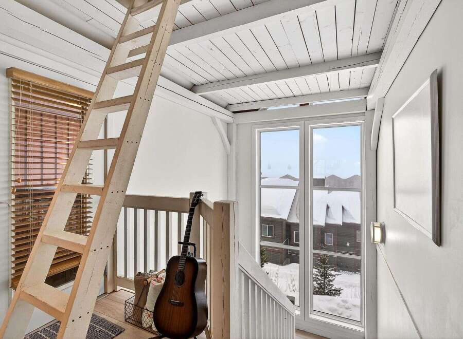 This charming property features a cozy loft space accessible by a rustic wooden ladder, perfect for a home office or guest area.