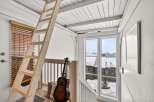 This charming property features a cozy loft space accessible by a rustic wooden ladder, perfect for a home office or guest area.