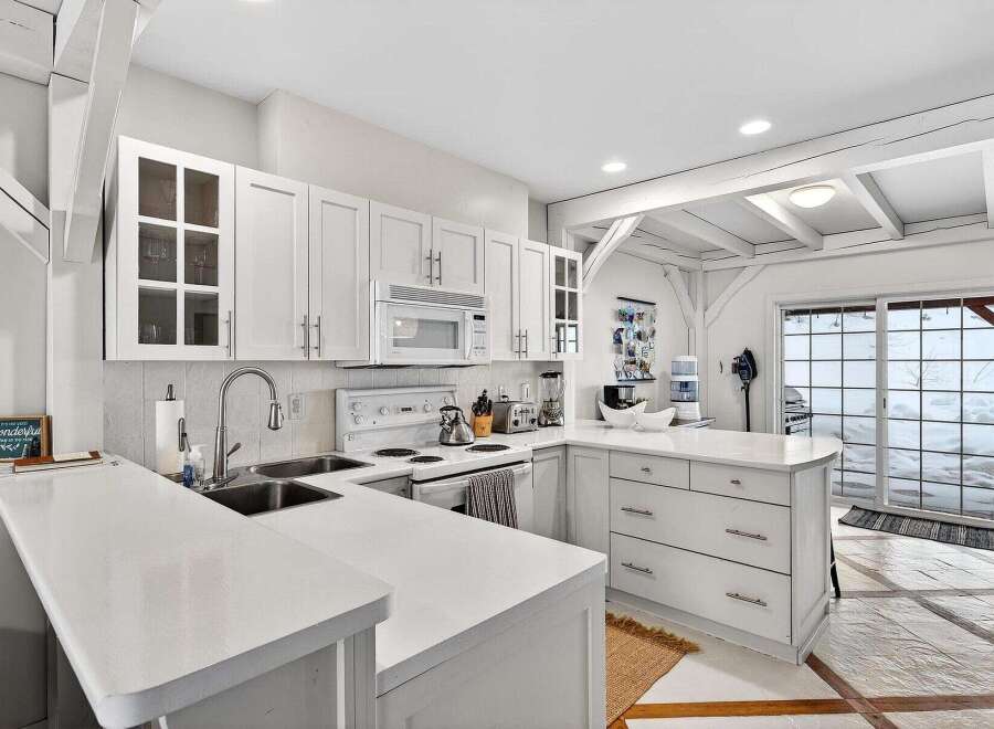 This stunning kitchen boasts a bright and airy design with pristine white cabinetry and countertops, creating a clean and modern aesthetic.