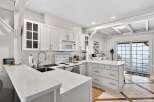 This stunning kitchen boasts a bright and airy design with pristine white cabinetry and countertops, creating a clean and modern aesthetic.