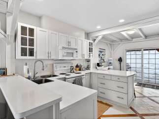 This stunning kitchen boasts a bright and airy design with pristine white cabinetry and countertops, creating a clean and modern aesthetic.