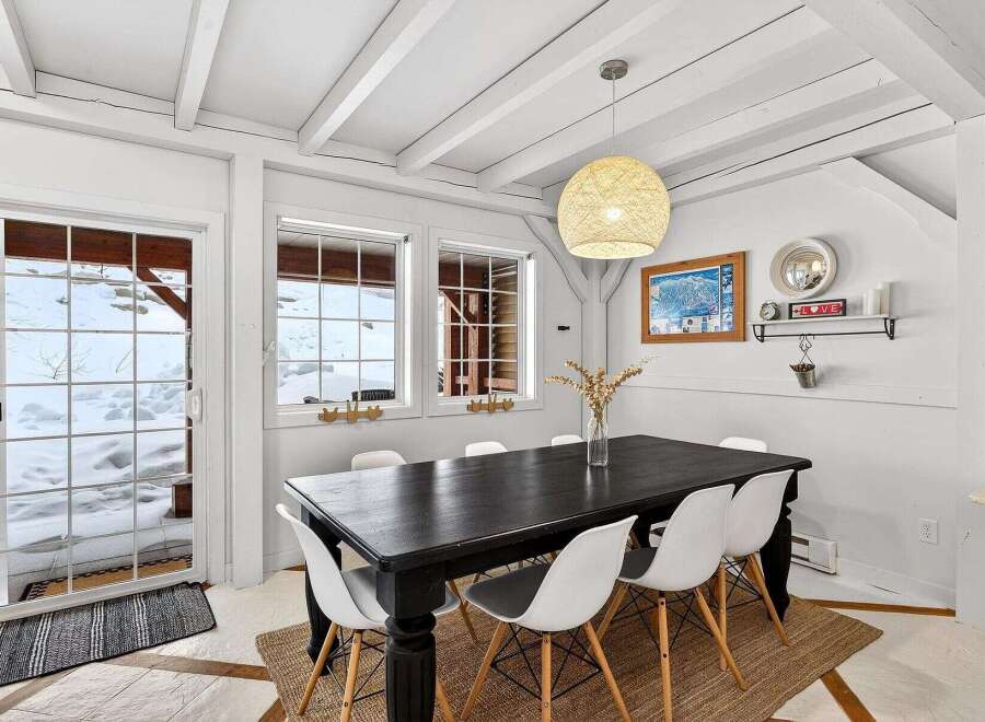 This charming dining room features a rustic aesthetic with a dark wood dining table and stylish white chairs.