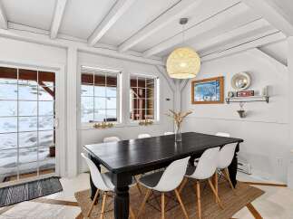 This charming dining room features a rustic aesthetic with a dark wood dining table and stylish white chairs.