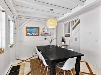 This charming dining room features a stylish black dining table and modern white chairs, perfect for hosting gatherings.
