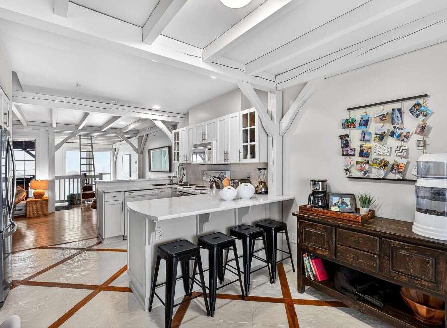 This stunning kitchen boasts a bright and airy design with exposed beams and a modern aesthetic.