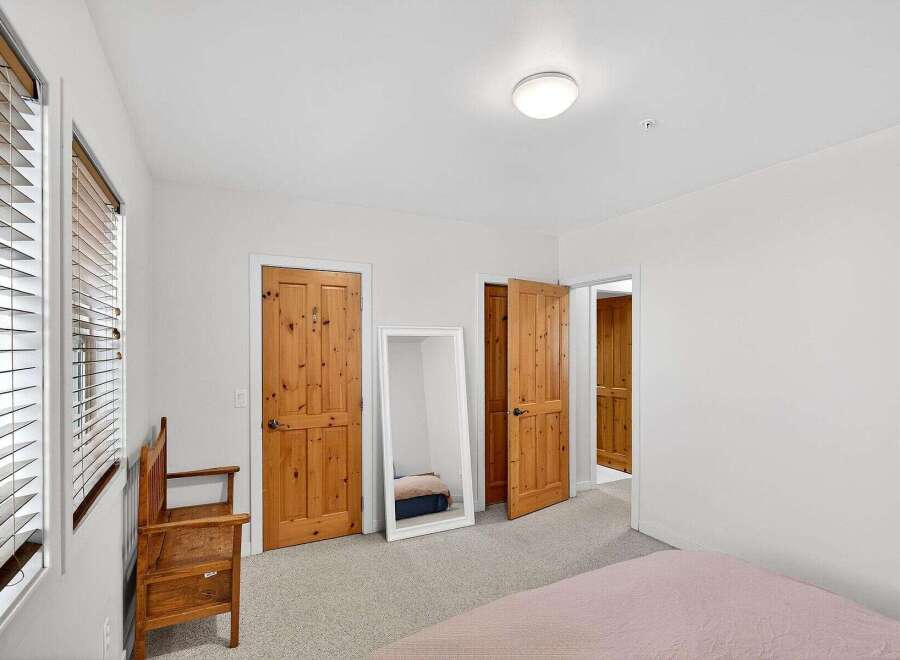 Step into this inviting bedroom, featuring warm wooden doors and a full-length mirror that amplifies the natural light.