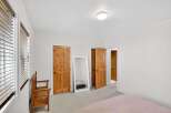 Step into this inviting bedroom, featuring warm wooden doors and a full-length mirror that amplifies the natural light.