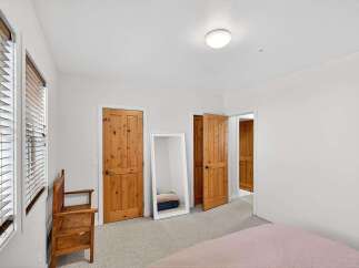 Step into this inviting bedroom, featuring warm wooden doors and a full-length mirror that amplifies the natural light.