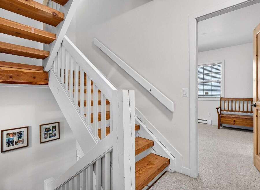 This stunning property features a beautifully crafted staircase with wooden steps and white railings, creating a warm and inviting atmosphere.