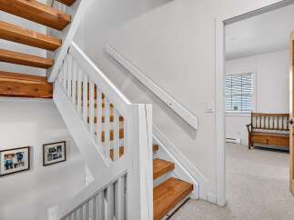 This stunning property features a beautifully crafted staircase with wooden steps and white railings, creating a warm and inviting atmosphere.