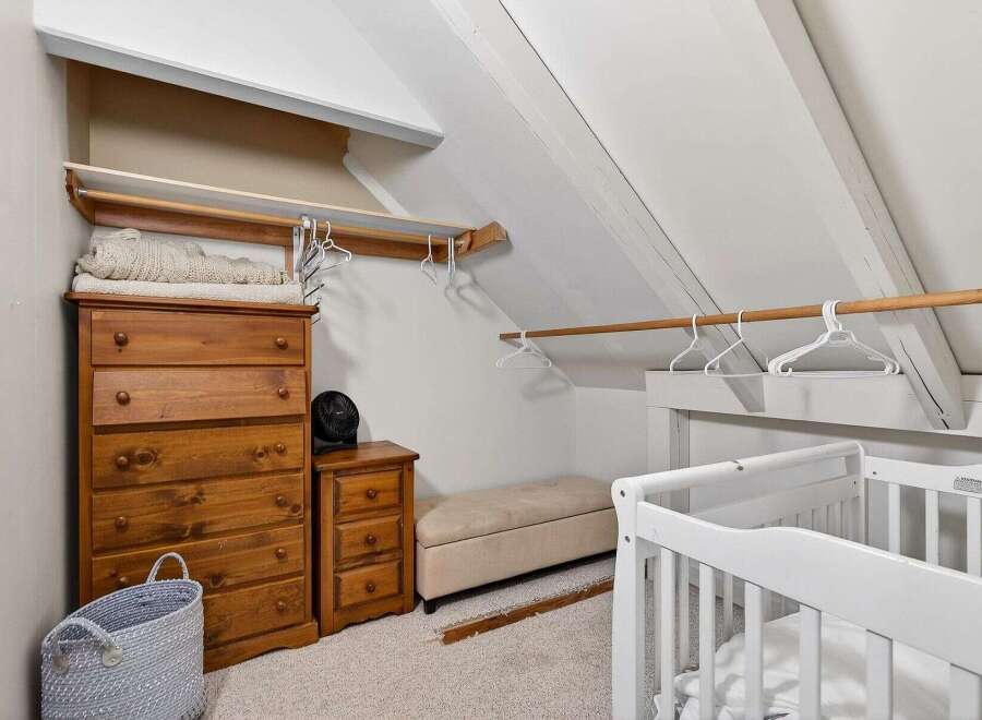 This charming nursery features a cozy, slanted-ceiling design, perfect for creating a warm and inviting space.