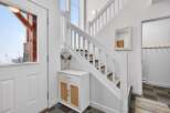 Step into this inviting entryway, showcasing a stylish staircase and a charming white cabinet with woven accents.