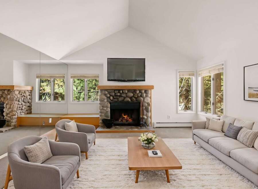 Experience the warmth of this stunning living room, featuring a cozy stone fireplace and a large flat-screen TV.