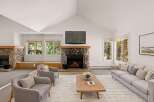 Experience the warmth of this stunning living room, featuring a cozy stone fireplace and a large flat-screen TV.