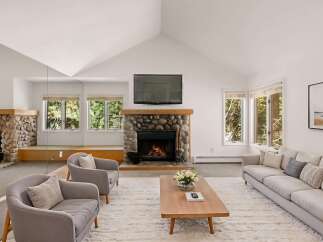Experience the warmth of this stunning living room, featuring a cozy stone fireplace and a large flat-screen TV.