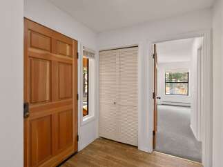 Step into this inviting entryway, showcasing a warm wooden door and a convenient closet.