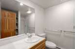 This bathroom features a bright and airy design with a large mirror and a clean, white aesthetic.