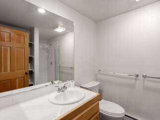 This bathroom features a bright and airy design with a large mirror and a clean, white aesthetic.
