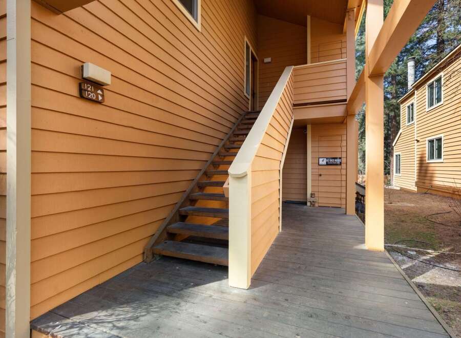 Discover the charm of this inviting property, featuring a welcoming exterior with a wooden deck and staircase.