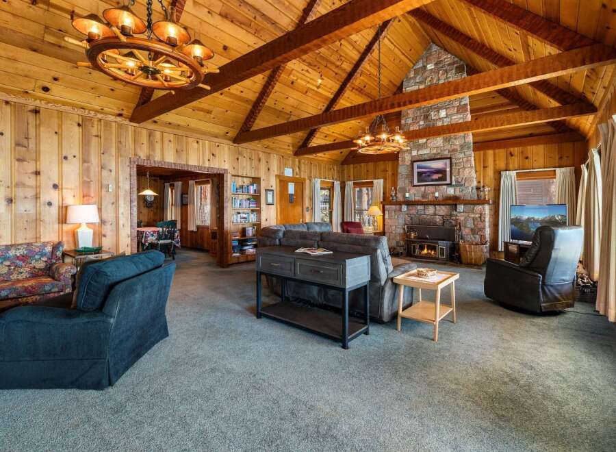 Step into luxury with this stunning property featuring a cozy living room with a fireplace and a rustic wooden ceiling.